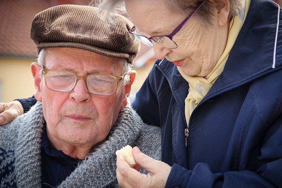 Zwei Senioren, die Frau gibt dem Mann ein Stück Brot zu essen